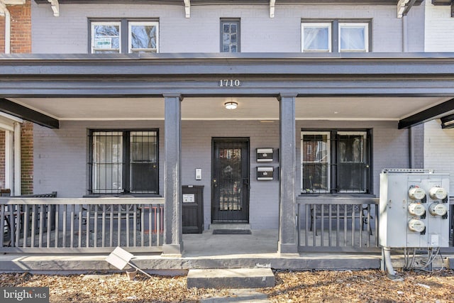 doorway to property with covered porch and brick siding