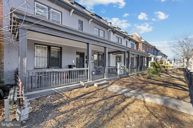 view of front facade featuring a residential view, fence, a porch, and brick siding