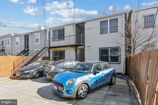 townhome / multi-family property featuring fence and stairs