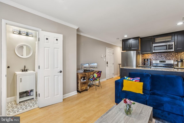 kitchen with crown molding, light wood finished floors, tasteful backsplash, appliances with stainless steel finishes, and dark cabinetry