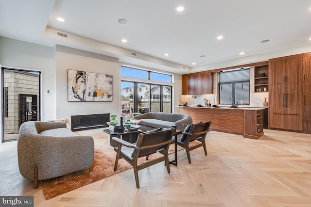 living area with a glass covered fireplace, visible vents, and recessed lighting