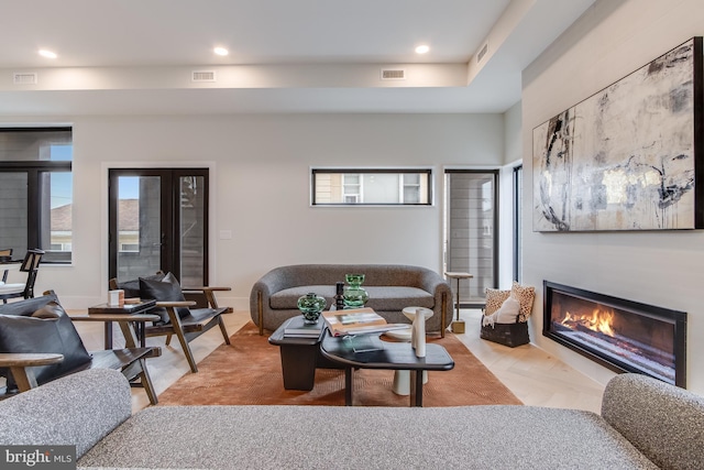 living area with recessed lighting, a fireplace with flush hearth, visible vents, and french doors