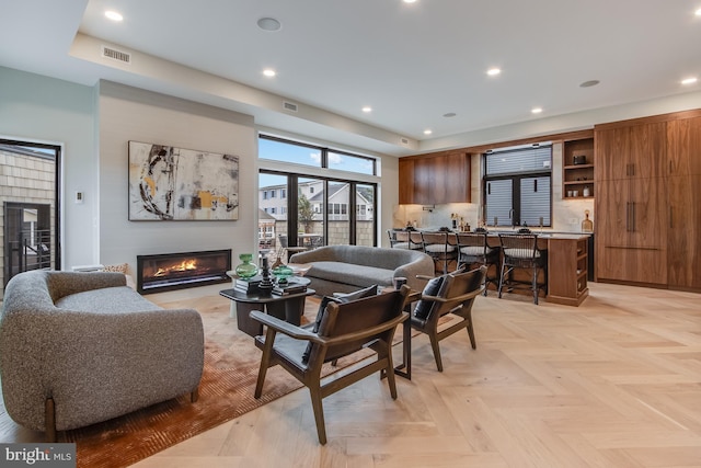 living area with a glass covered fireplace, visible vents, and recessed lighting