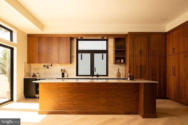 kitchen with brown cabinets, light countertops, decorative backsplash, and modern cabinets