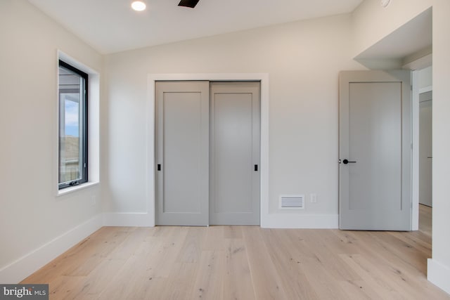 unfurnished bedroom featuring baseboards, a closet, visible vents, and light wood-style floors