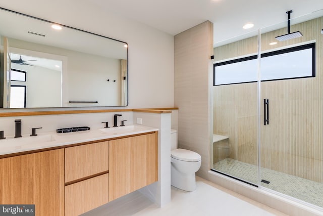 full bath with toilet, a stall shower, double vanity, and a sink