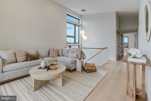 living room with light wood-type flooring, a towering ceiling, and a healthy amount of sunlight