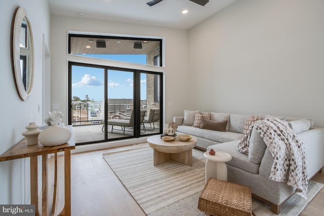 living room featuring a ceiling fan, recessed lighting, a towering ceiling, and wood finished floors