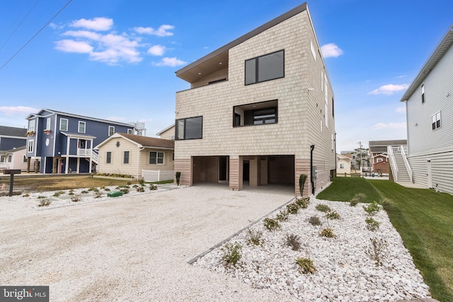 back of property with a garage, driveway, and a yard