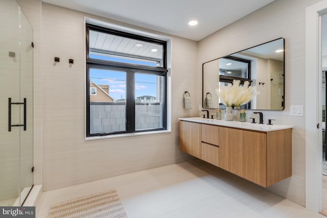 bathroom with a stall shower, a sink, and double vanity