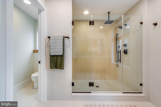 full bathroom featuring a stall shower, tile patterned flooring, toilet, and baseboards