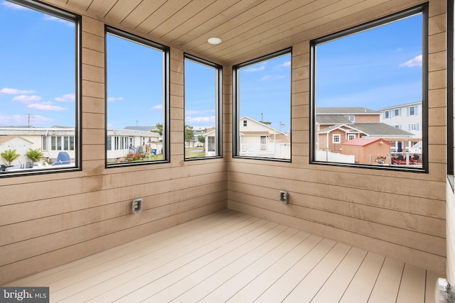 unfurnished sunroom with wood ceiling, plenty of natural light, and a residential view