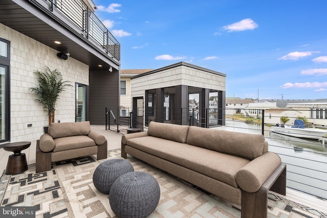 view of patio with an outdoor living space, a water view, and a balcony