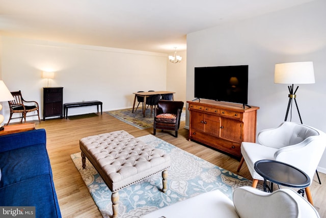 living area with an inviting chandelier, light wood-style flooring, and baseboards