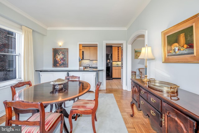 dining space featuring arched walkways and crown molding