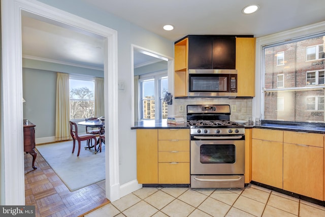 kitchen featuring baseboards, dark countertops, appliances with stainless steel finishes, crown molding, and backsplash