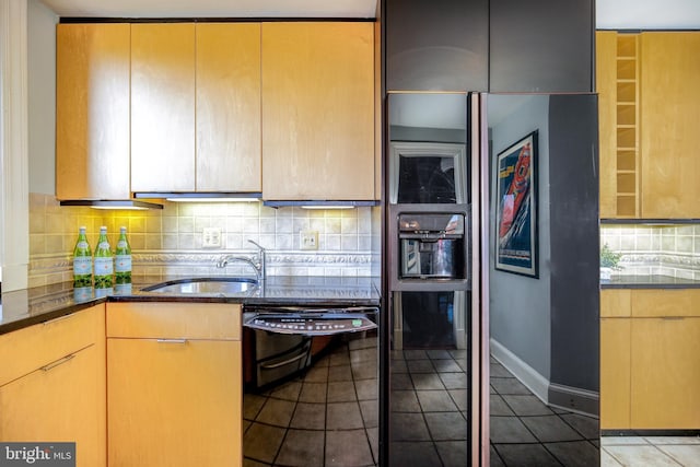 kitchen with dishwasher, backsplash, dark stone countertops, tile patterned flooring, and a sink