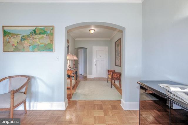 hallway featuring arched walkways, crown molding, and baseboards