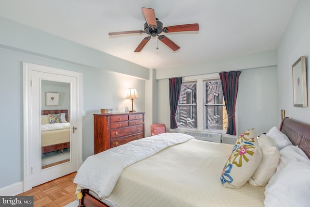 bedroom with a wall unit AC, ceiling fan, and baseboards