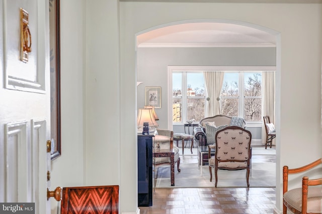 living area featuring ornamental molding and arched walkways