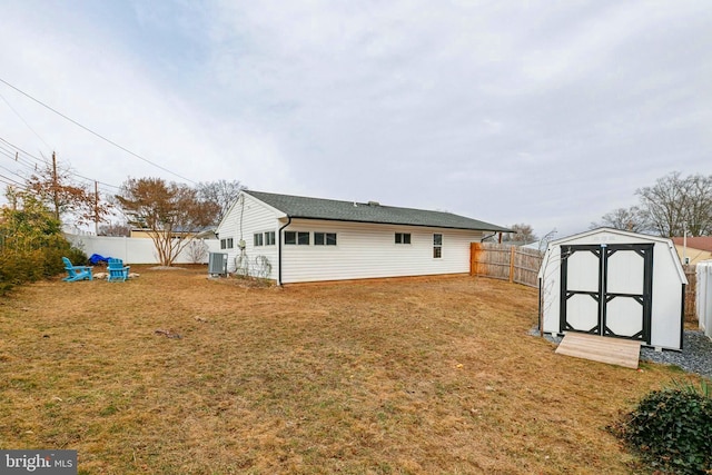 back of property with an outbuilding, a fenced backyard, a lawn, and a storage shed