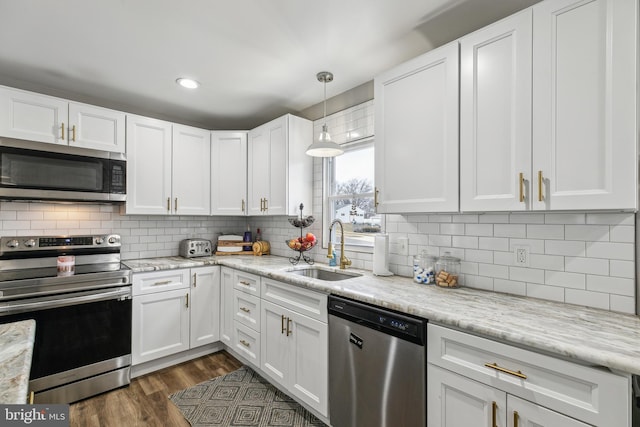 kitchen with stainless steel appliances, dark wood-type flooring, a sink, white cabinets, and backsplash