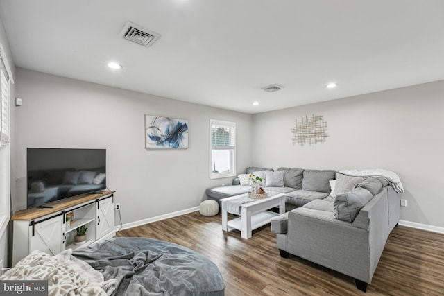 living area featuring visible vents, baseboards, and wood finished floors