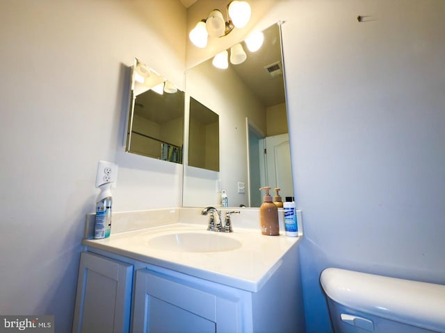 bathroom featuring visible vents, toilet, and vanity