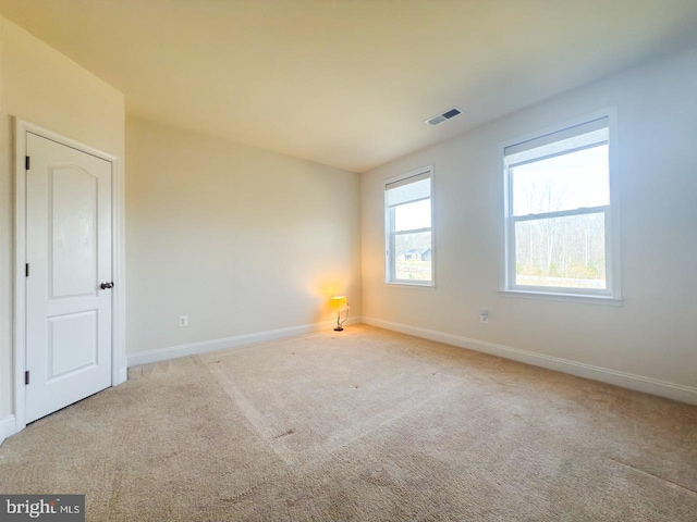 carpeted empty room featuring baseboards and visible vents