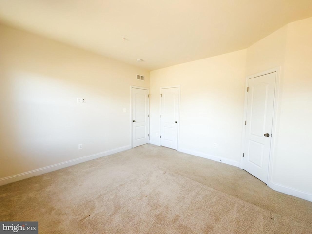 unfurnished room with visible vents, light carpet, and baseboards