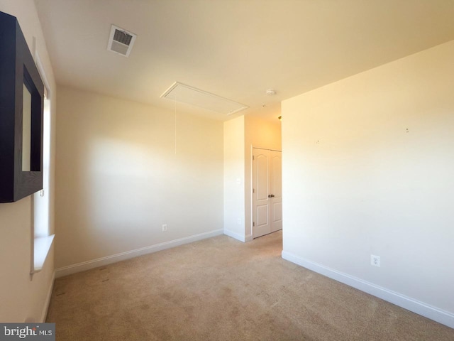 unfurnished room featuring attic access, baseboards, visible vents, and light carpet