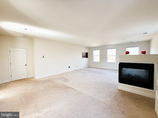 unfurnished living room with visible vents, carpet, a multi sided fireplace, and baseboards