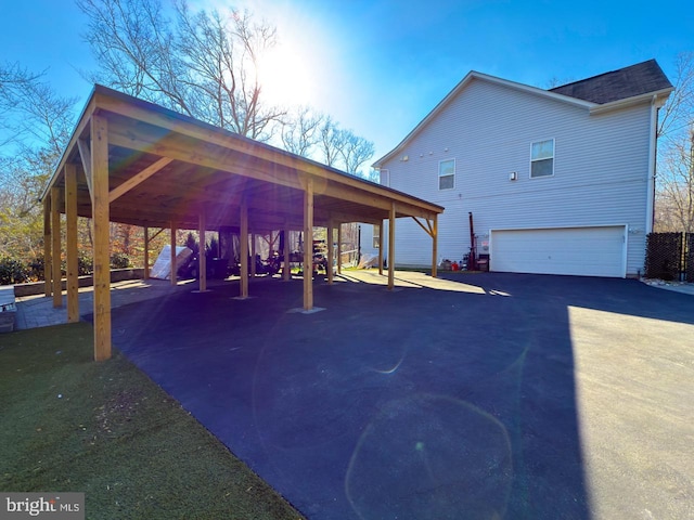 exterior space featuring a carport, driveway, a shingled roof, and a garage