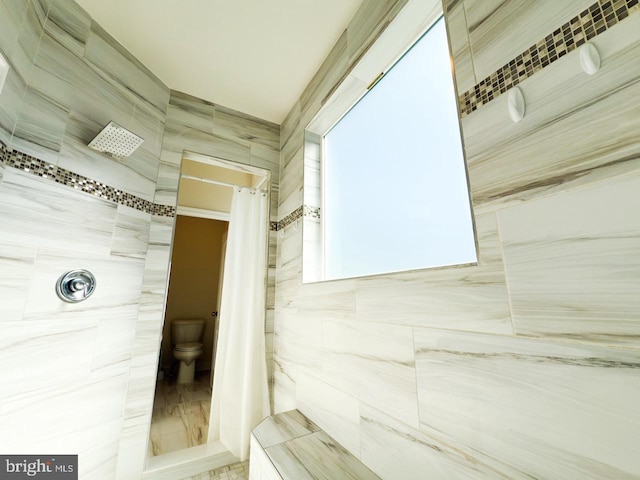 full bathroom featuring tiled shower and toilet