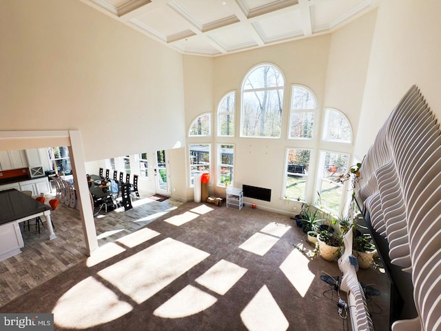 interior space with beam ceiling, a towering ceiling, baseboards, and coffered ceiling