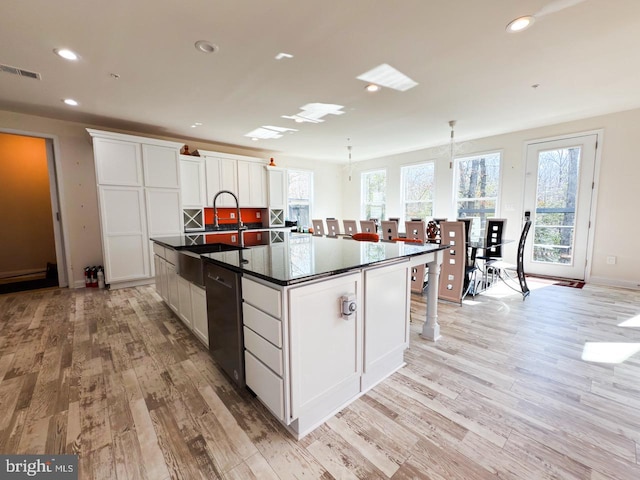 kitchen with visible vents, black dishwasher, dark countertops, white cabinets, and light wood finished floors