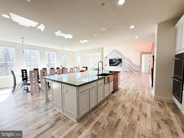 kitchen with light wood-style flooring, recessed lighting, open floor plan, and a sink