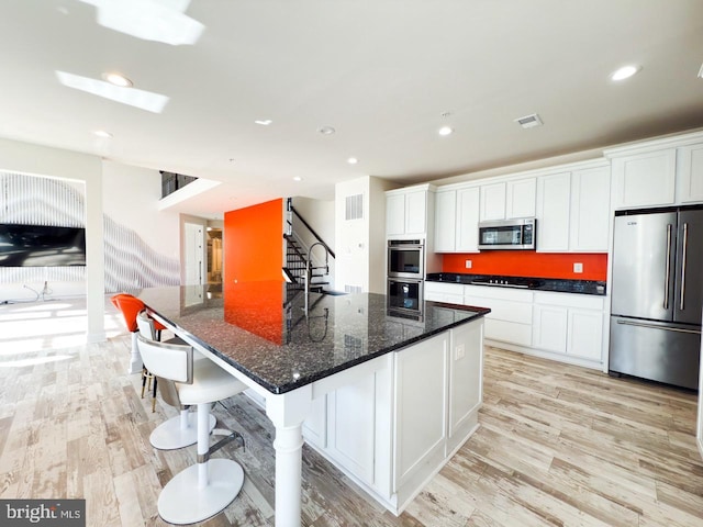 kitchen with visible vents, a sink, stainless steel appliances, light wood-style floors, and white cabinets