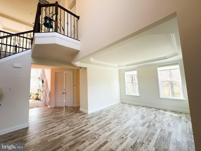 interior space with stairway, a raised ceiling, baseboards, and wood finished floors