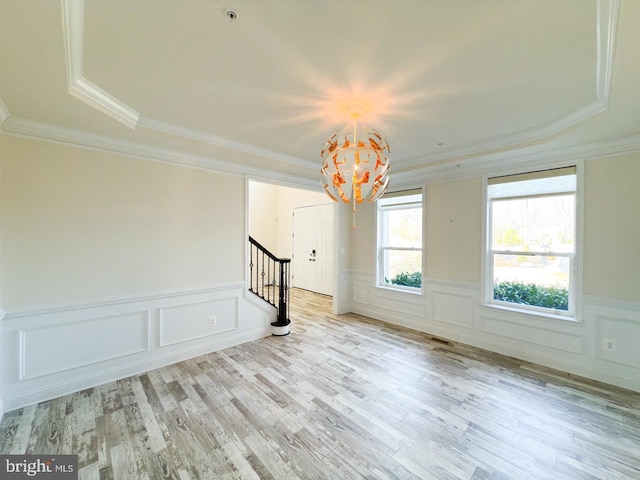 unfurnished room featuring a wainscoted wall, ornamental molding, stairs, and wood finished floors