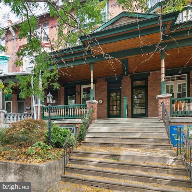 entrance to property with covered porch and brick siding