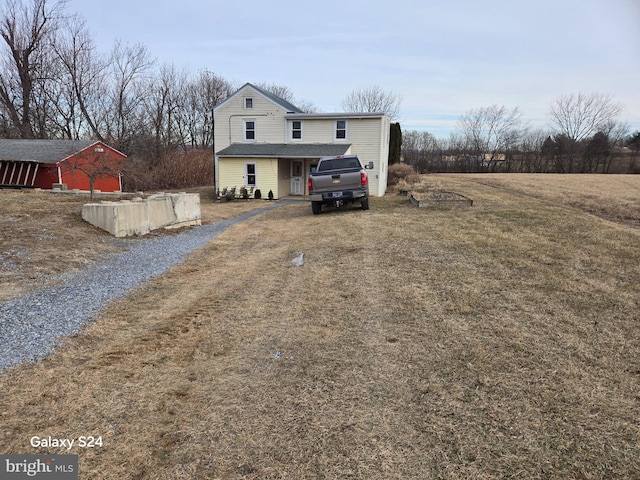 traditional-style home featuring a front yard and gravel driveway