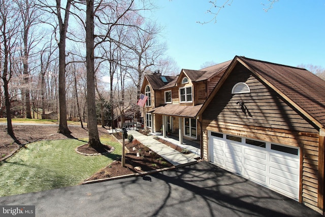 view of front of home with covered porch, a chimney, an attached garage, and aphalt driveway