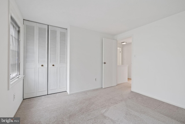 unfurnished bedroom with a closet, baseboards, and light colored carpet