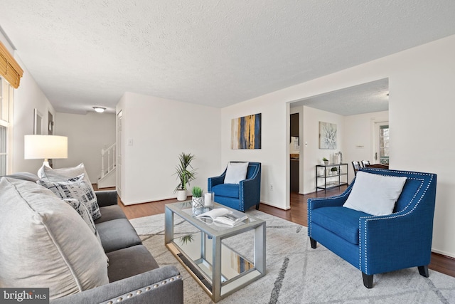 living room with a textured ceiling, wood finished floors, and stairway