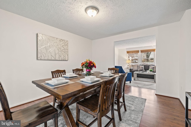 dining space featuring baseboards, a textured ceiling, and dark wood finished floors