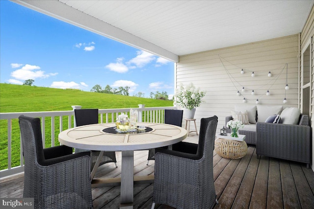 wooden terrace featuring outdoor dining area and a lawn