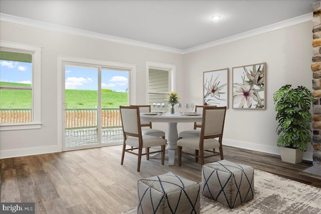 dining room featuring crown molding, baseboards, and wood finished floors