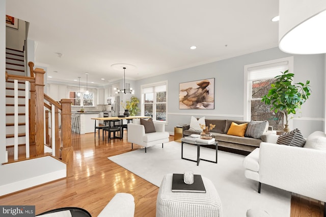 living area with stairway, an inviting chandelier, light wood-style flooring, and recessed lighting