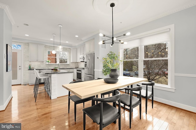 dining room with baseboards, light wood-style flooring, and crown molding